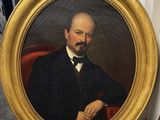 portrait of a man in a black suit and bow tie sitting in a red chair