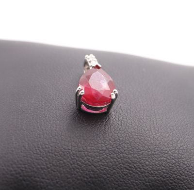 a close up of a red tear shaped stone on a black purse