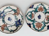 two plates with floral designs on them on a white surface