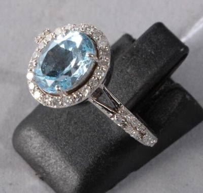 a close up of a ring with a blue topaz stone surrounded by diamonds