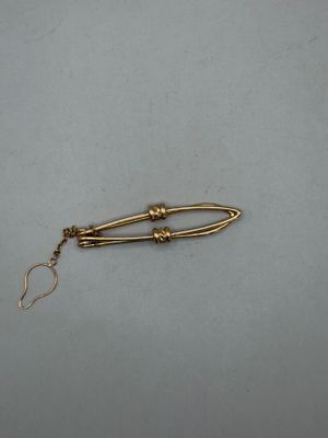 a close up of a gold pin with a chain attached to it