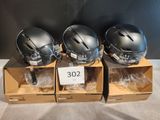 three helmets are sitting in boxes on a table with a price tag