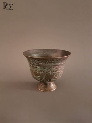 a silver bowl sitting on a table with a brown background
