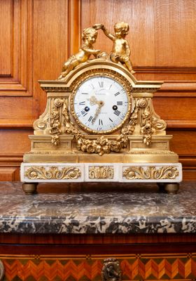 a gold clock sitting on top of a marble table