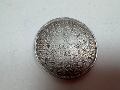 an old silver coin sitting on top of a white surface