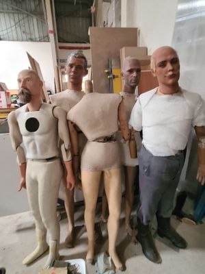 plusieurs mannequins dans un atelier, avec un homme debout à côté d'eux