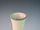 a white and green vase sitting on a table