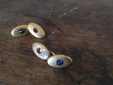 une paire de boucles d'oreilles en or et pierres bleues posées sur une table en bois
