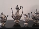 five silver teapots sitting on a black table