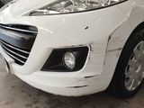 a white car that has been dented and is parked in a garage