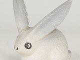 a small white rabbit figurine sitting on a white surface