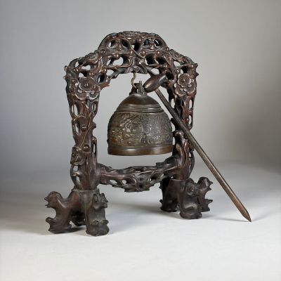 une cloche en métal surmontée d'une épée, posée sur un socle