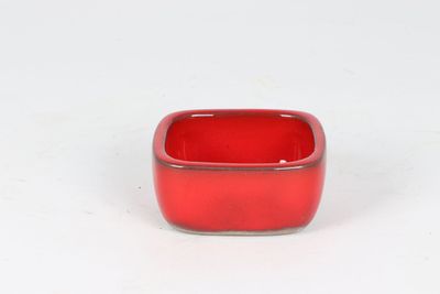 un petit bol rouge posé sur une surface blanche