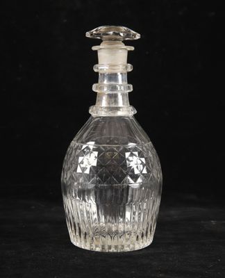 une bouteille en verre transparent munie d'un bouchon, posée sur une surface noire