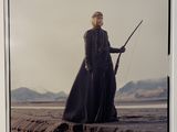 an old photo of a woman in a long black dress holding a sword