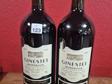 two bottles of wine sitting on top of a wooden table next to a red wall