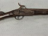 un vieux fusil exposé sur une surface blanche
