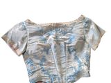 the top of a women ' s shirt with blue and white flowers on it