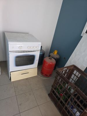une cuisinière blanche posée dans une cuisine, à côté d'un réfrigérateur