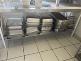 several pans are stacked on a stainless steel shelf in a kitchen