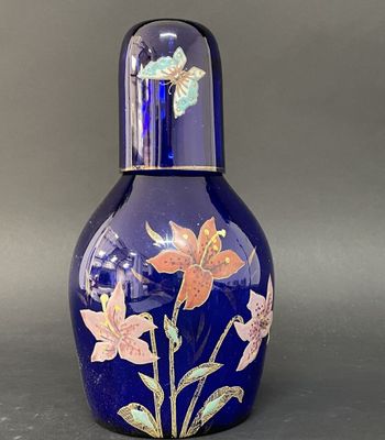 un vase en verre bleu orné de fleurs et de papillons peints