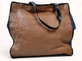 brown and blue handbag sitting on a white surface with a white background