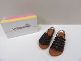 black leather sandals with black straps on a white surface next to a box