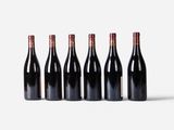 six bottles of wine lined up in a row on a white surface