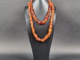 un collier composé de perles de cornaline et de perles orange, présenté sur un mannequin noir