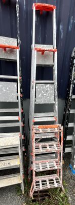 several ladders are stacked next to each other in front of a building