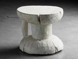 une petite table blanche avec un piètement en bois posée sur un sol en béton