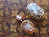two pieces of jewelry sitting on top of a wooden table