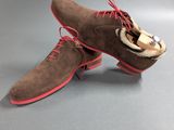 a pair of brown sued shoes with red laces on them