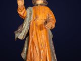 wooden statue of a man with a beard and robe holding a cross