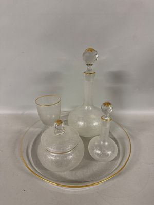a glass plate with a glass decanter and a glass cup on it