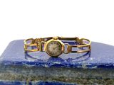 une montre-bracelet posée sur un bloc de marbre bleu avec un fond blanc