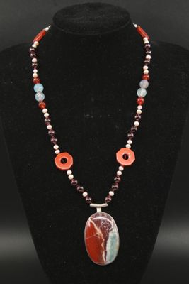 un collier orné d'un pendentif en pierre rouge, blanche et bleue, posé sur un mannequin noir