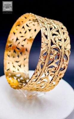 a close up of a gold bracelet on a white plate