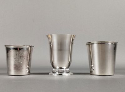 trois coupes en argent sont alignées les unes à côté des autres sur une table
