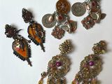 cinq paires de boucles d'oreilles et une broche posées sur une table