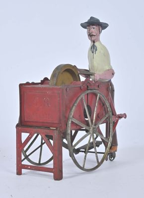 a toy of a man sitting in a wagon with a wheel