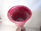 a pink glass vase sitting on a table next to a remote control
