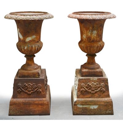 pair of antique cast iron urns on pedestals on a white background