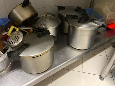 Plusieurs casseroles et poêles sont posées sur une étagère métallique dans une cuisine.