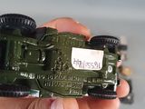 a person holding a toy army vehicle in their hand