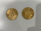 two pieces of gold coins sitting on top of a white surface