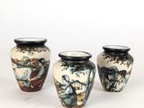 Trois vases sont posés sur une surface blanche ; l'un d'entre eux est orné d'une peinture.
