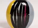 a black, yellow, and white marble ball on a white surface