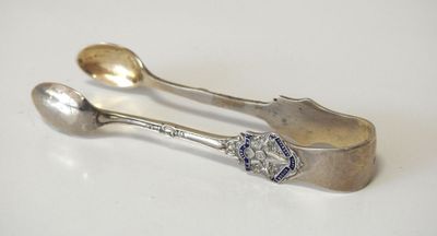 two silver spoons and a spoon rest on a white surface