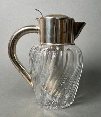 a glass pitcher with a metal handle on a table